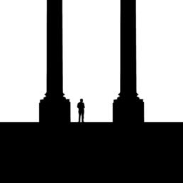 Silhouette of a lone person standing between massive architectural columns against a stark white background.