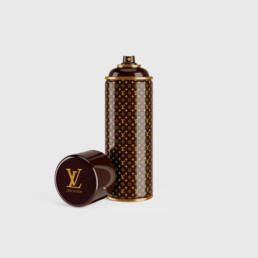 A designer-style spray paint can featuring a Louis Vuitton monogram pattern in brown and gold, with the cap removed and resting beside it.